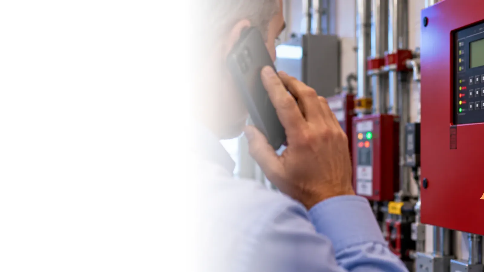 Building manager on a phone call next to a fire alarm control panel with an orange deficiency tag